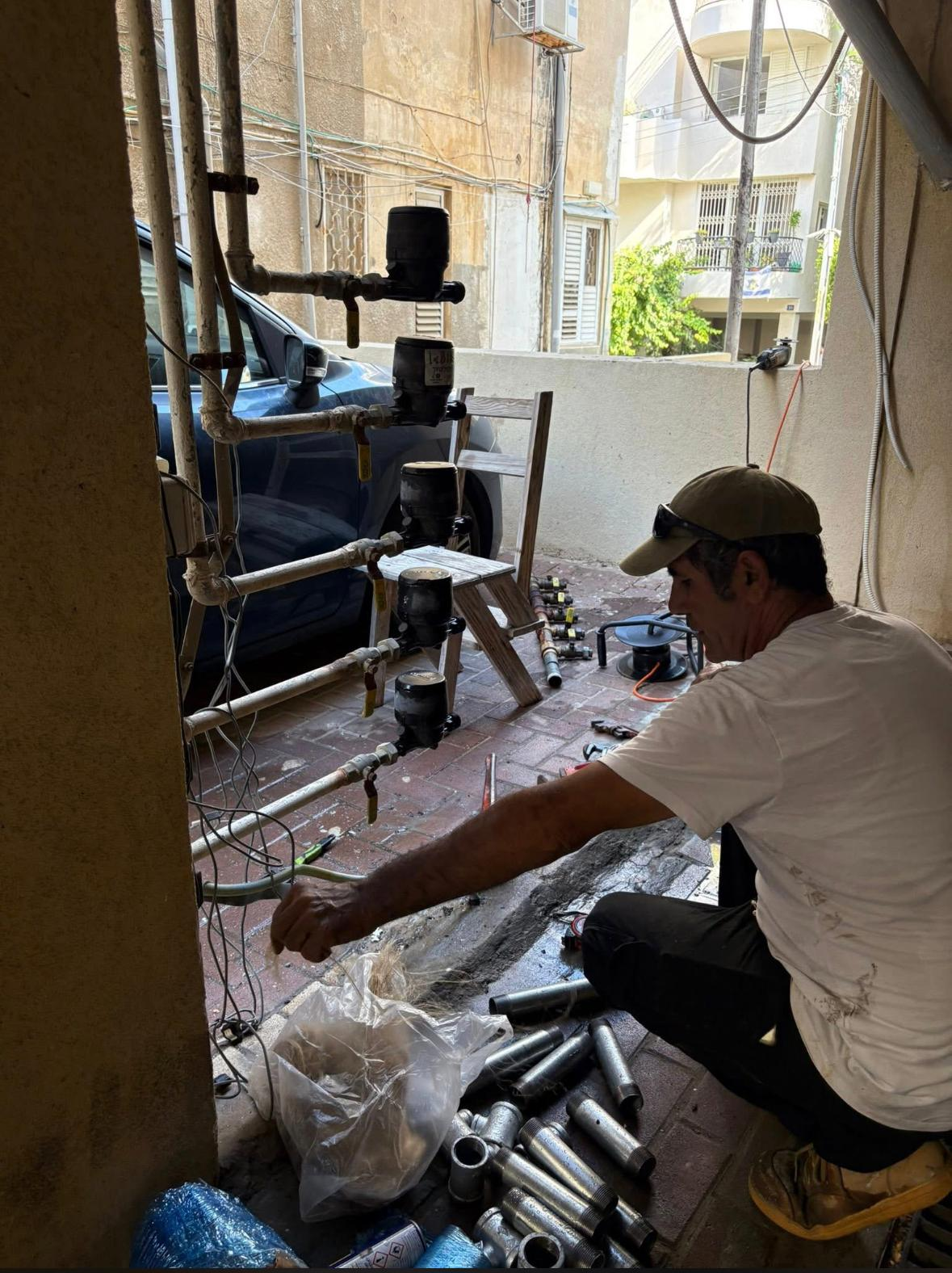 בעל מקצוע במהלך התקנת חנוכיית מים חדשה בבניין משותף
